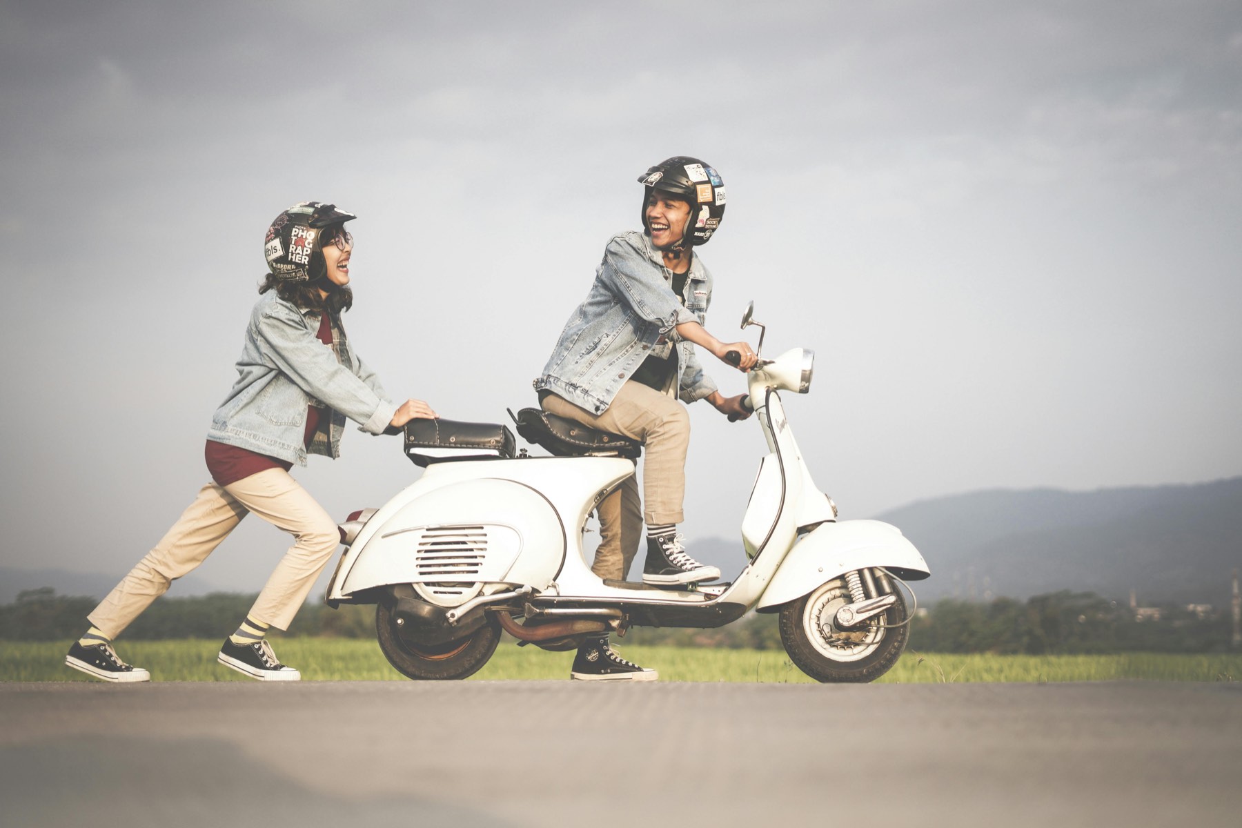 Zwei Personen mit Helm auf einem weißen Motorroller